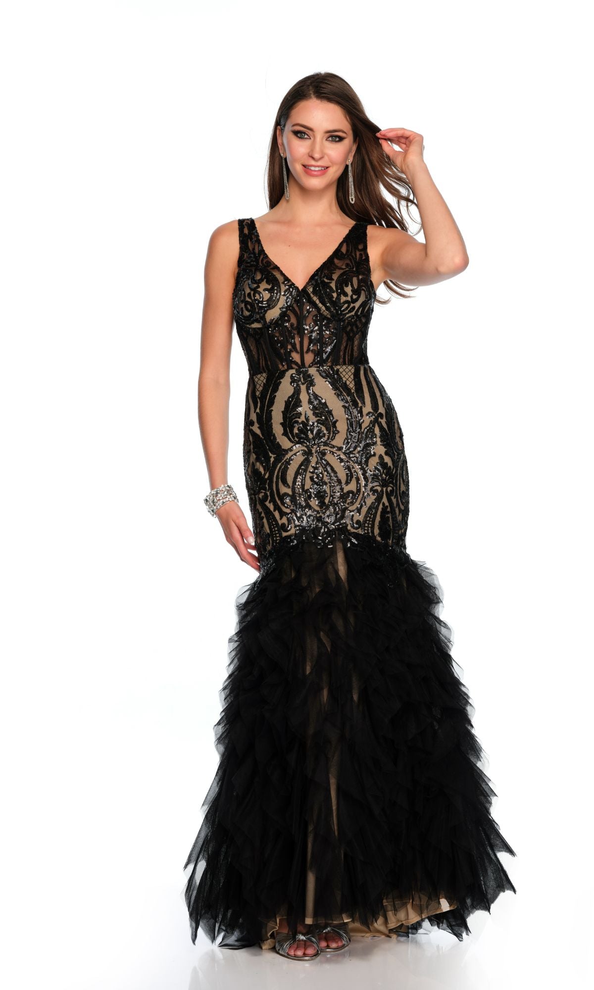 A woman poses against a plain white background in the Long Formal Dress 11325 by Dave and Johnny, featuring a sleeveless black and nude mermaid silhouette with a v-neckline, sequined patterns, and a ruffled tulle skirt.